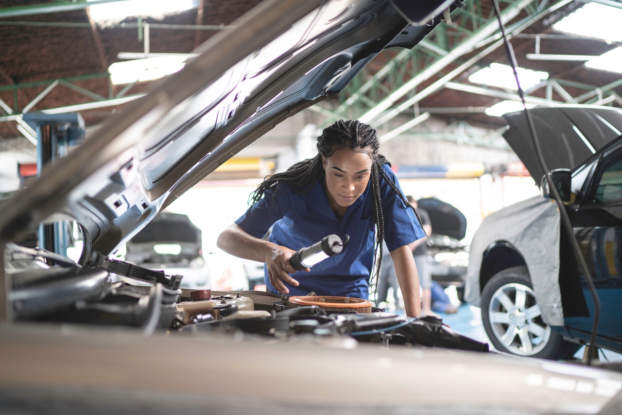 Woman repairing a car in auto repair shop - How API-enabled B2B will help “Open Everything” in the automotive industry