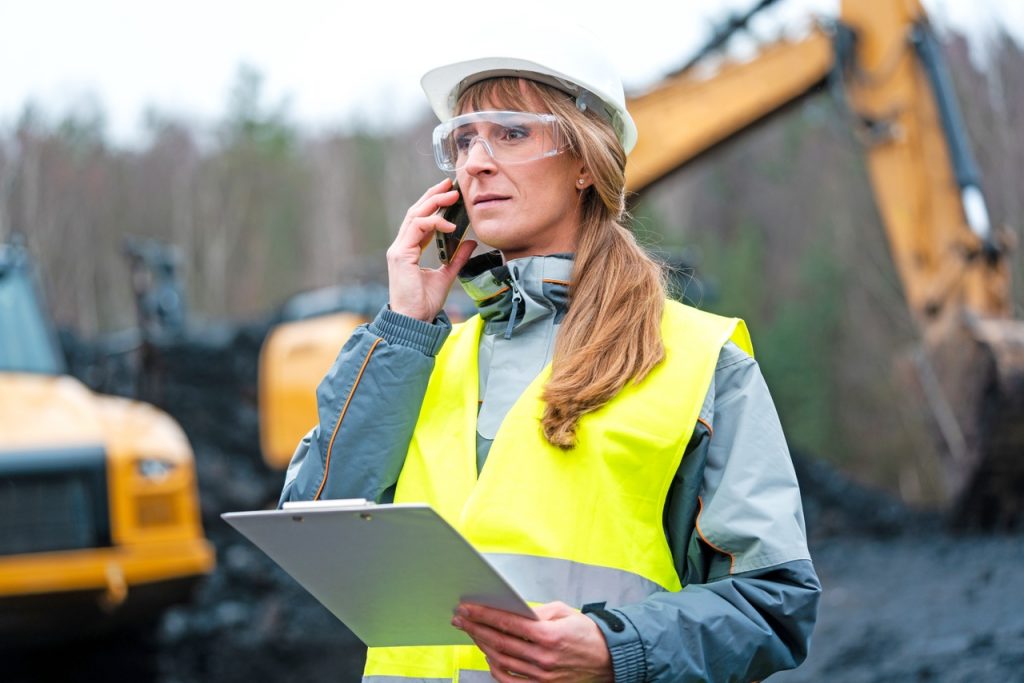 Worker woman in open-cast mining using phone