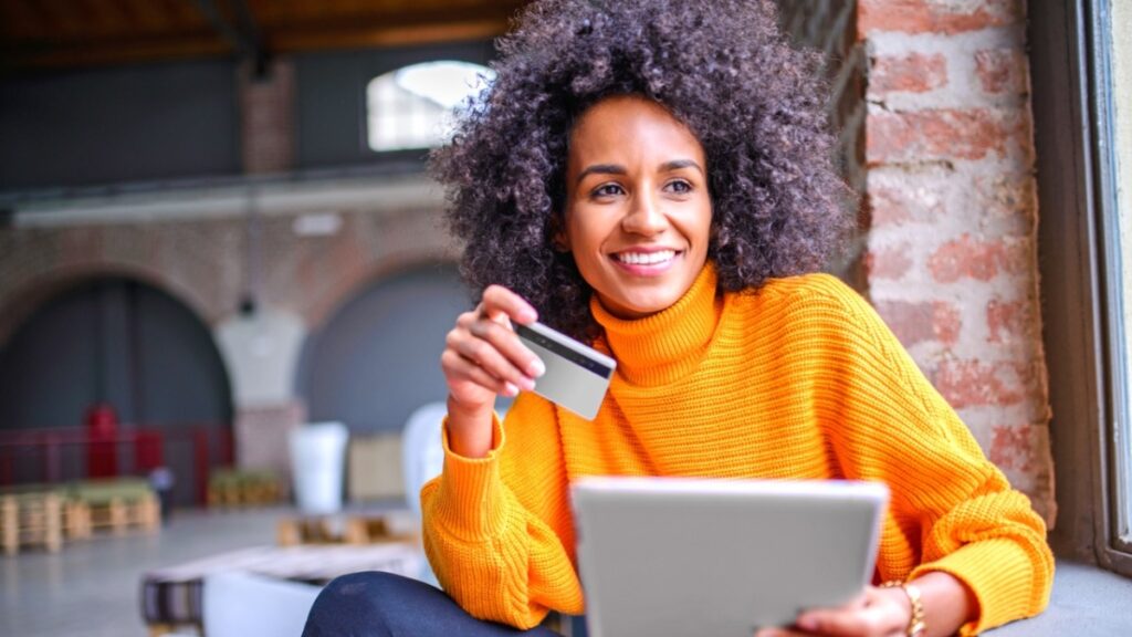 an image of a woman holding a credit card in her hand and smiling