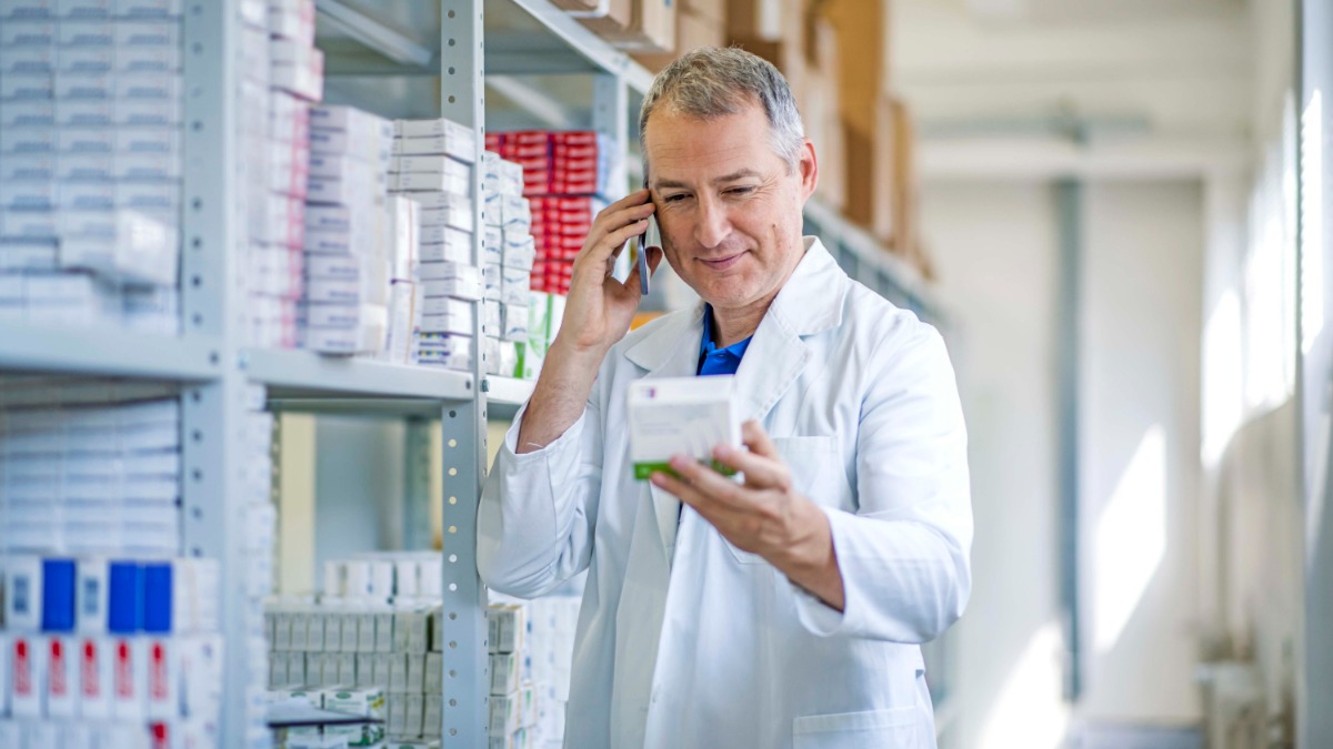 pharmacist on the phone while looking at a package of medication