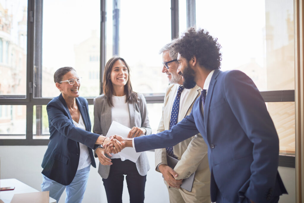 A group of people in a business meeting shaking hands.