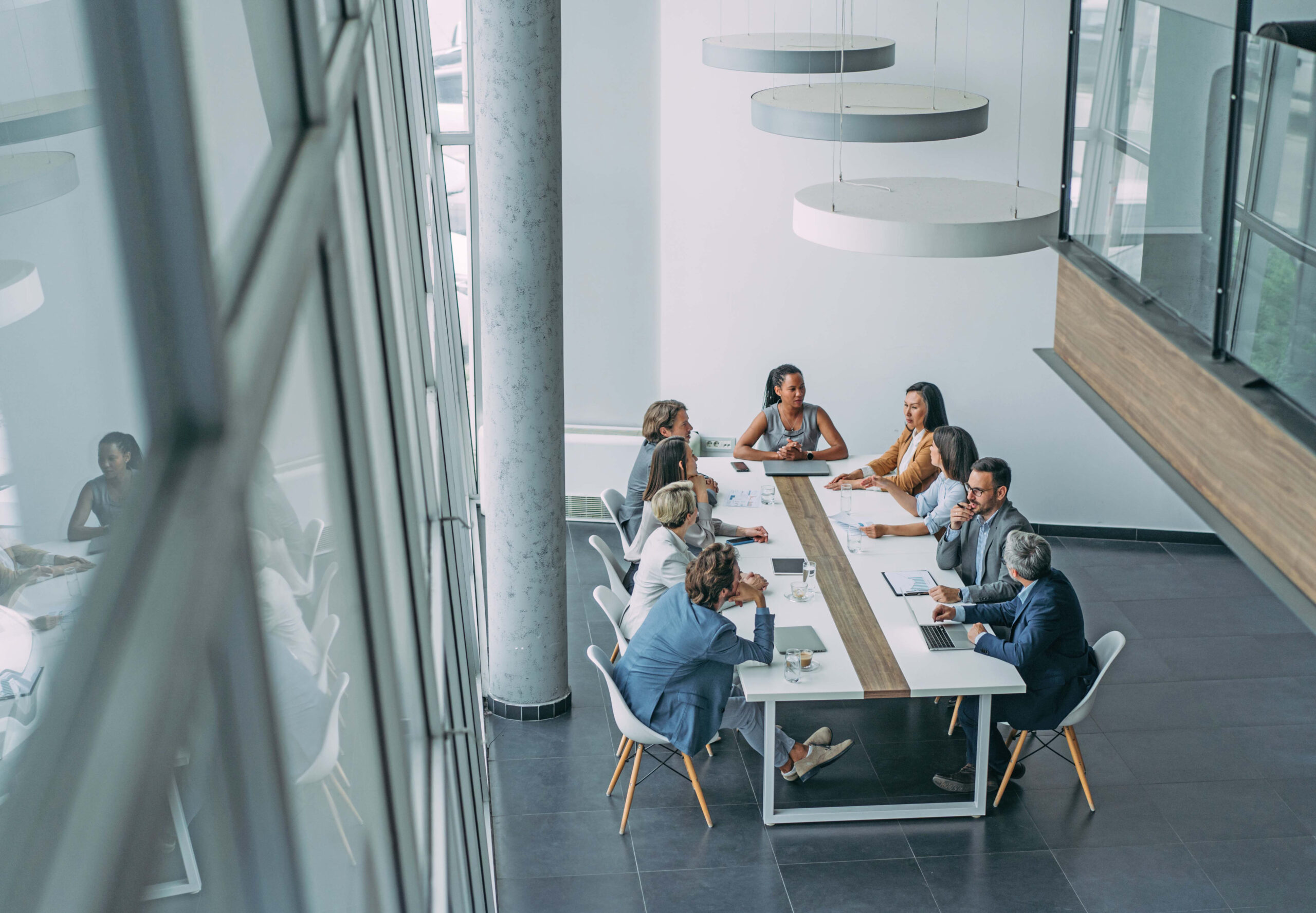 A group of people discussing work at a long white table in a modern office