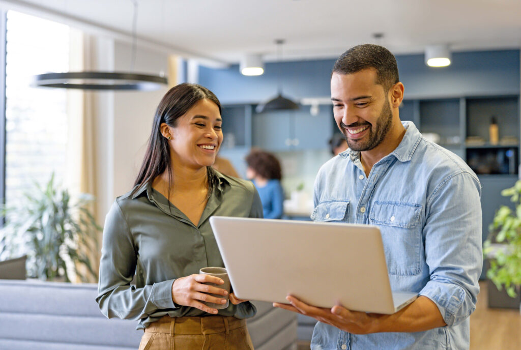 A man and a woman in an office, a man is holding a white laptop