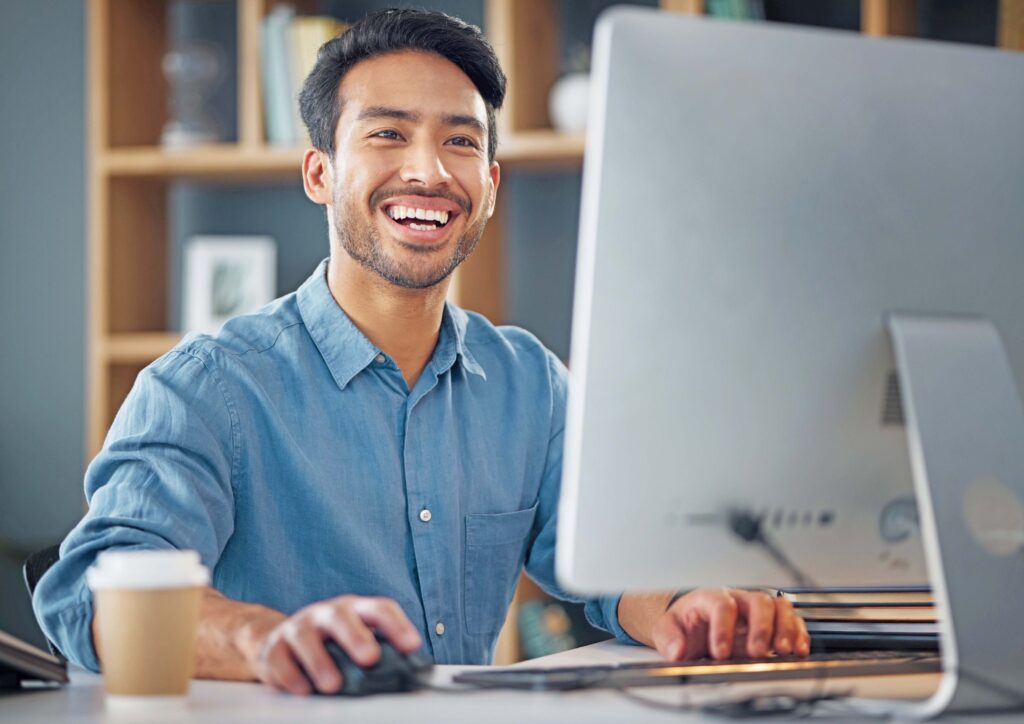 A man in a button-down is using a desktop computer