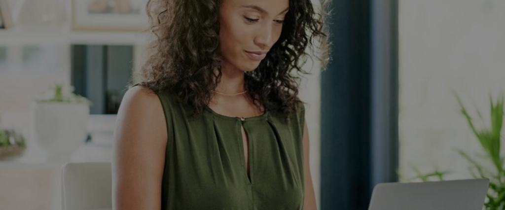 Woman in green shirt typing in a laptop, in the office