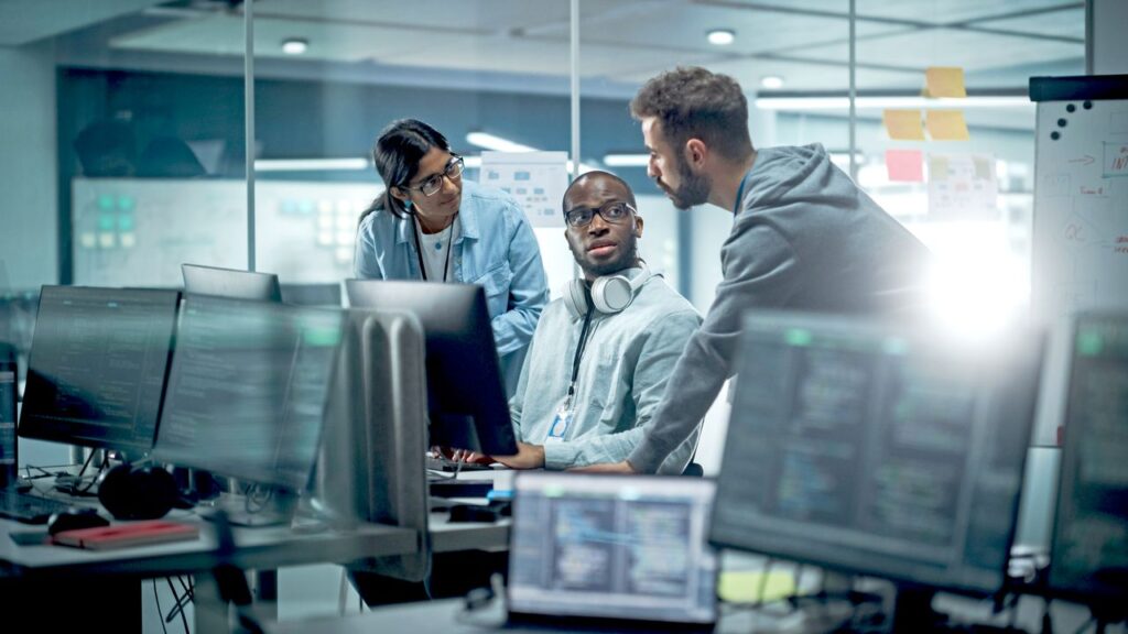 Diverse Group of Professionals Meeting in Modern Office: Brainstorming IT Programmers Use Computer Together, Talk Strategy, Discuss Planning. Software Engineers Developing