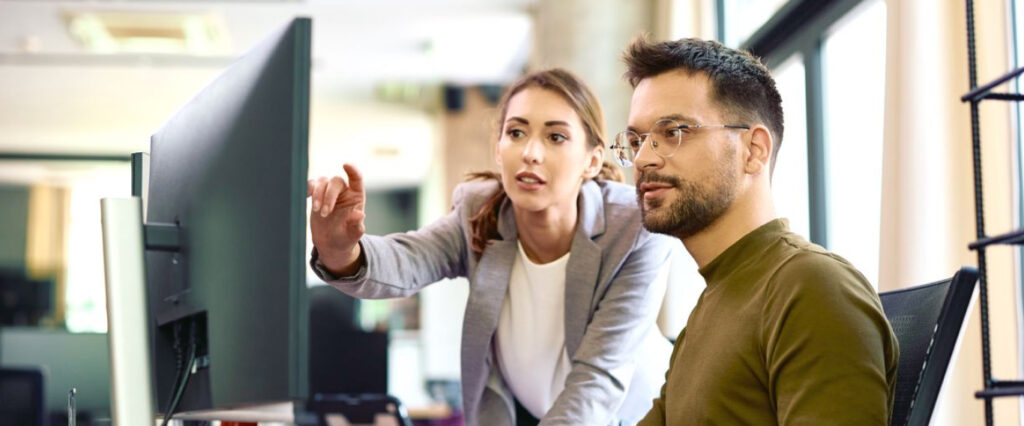 Woman showing and explaning something on a computer to a man