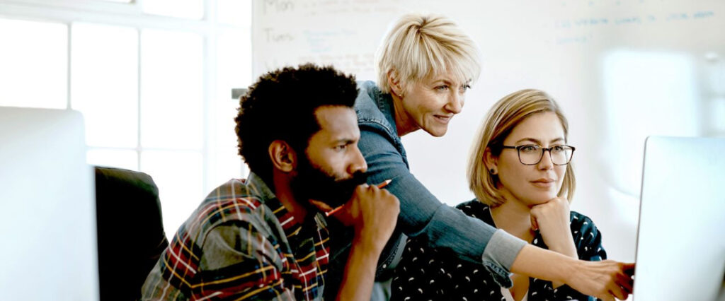 3 people looking at a computer screen, planning something