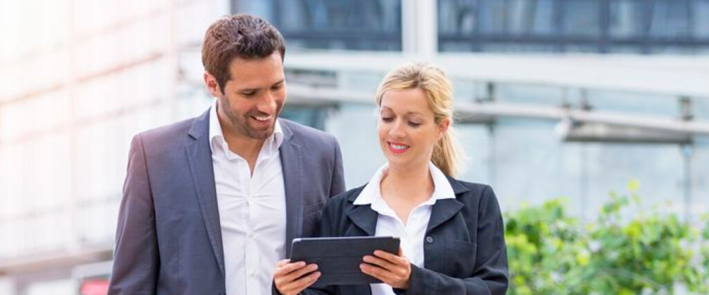 man and woman in suits looking at a tablet