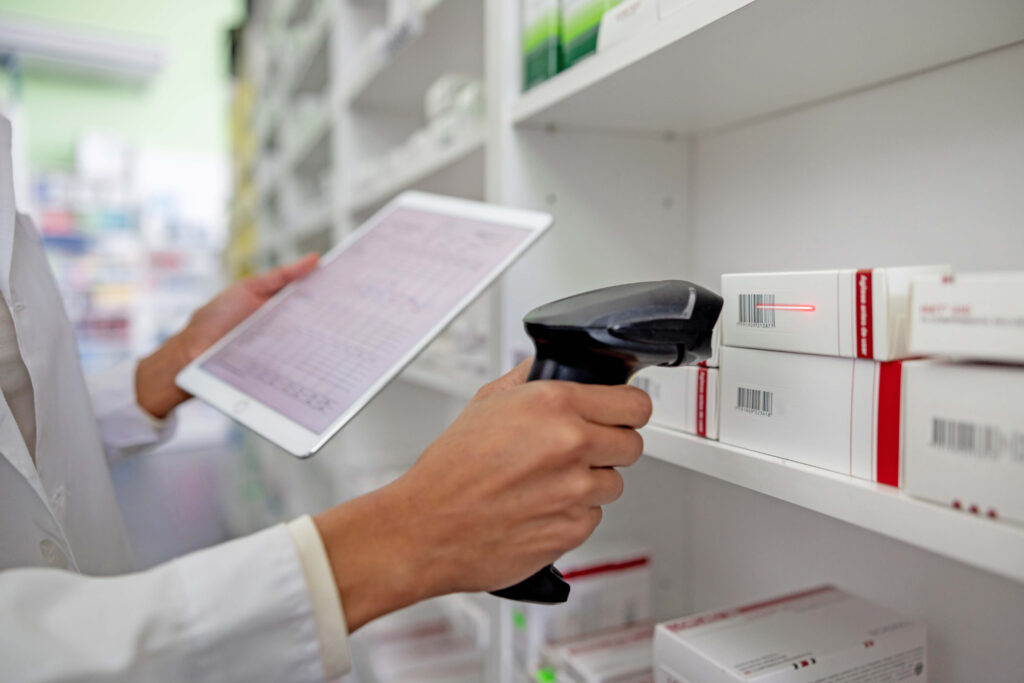 A pharmacist scanning a barcode for a medication on a shelf