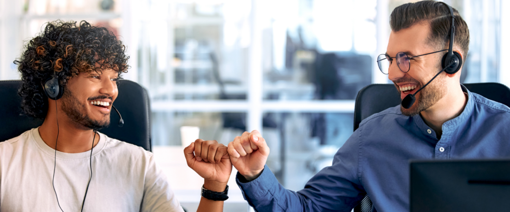 two men fist bumping each other in the office, smiling
